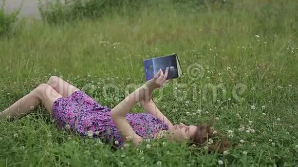 美丽的年轻女子在草地上读书视频的预览图