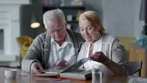 年长的幸福夫妇在一起怀旧他们看着旧相册微笑着视频的预览图