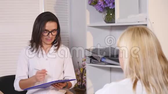 戴眼镜的营养师在笔记本上做笔记并与客户沟通视频的预览图
