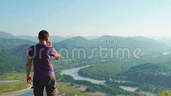 俄罗斯阿尔泰山地风景背景下的一个人在手机上讲话视频的预览图
