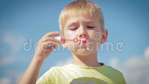 快乐的小男孩吹肥皂泡慢动作视频的预览图