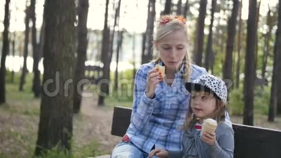 快乐的妈妈和小女儿在长凳上吃冰淇淋视频的预览图