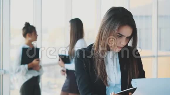 一位身穿白色西装手里拿着文件夹的漂亮黑发商务女性视频的预览图