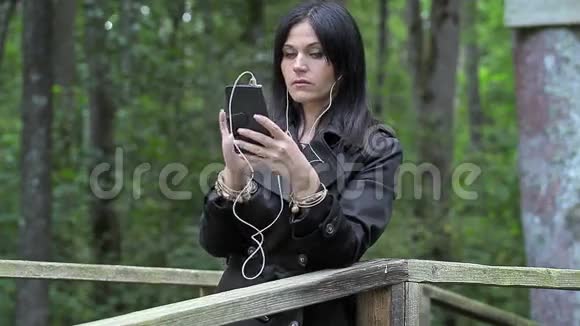 女人在公园的桥上听音乐视频的预览图