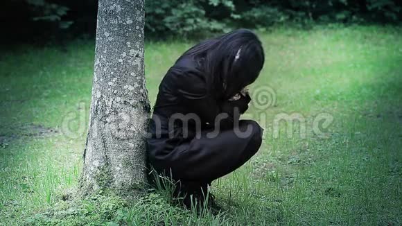 公园里树旁一个忧郁的女人视频的预览图