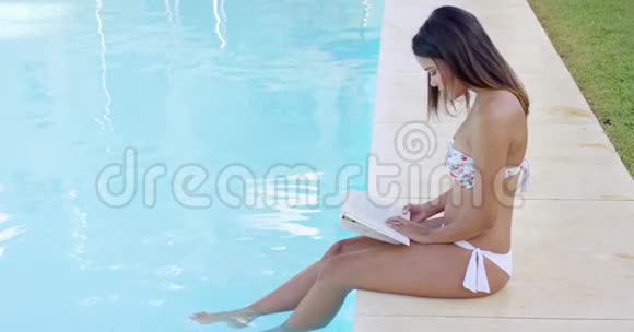 年轻女子在游泳池看书视频的预览图