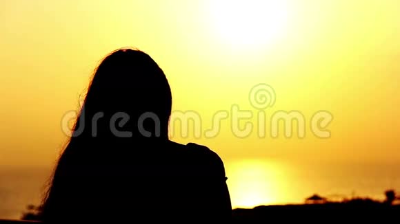 阳台上日落时分一个女人的剪影把她的头发贴在海边视频的预览图