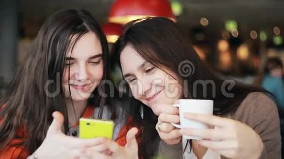 两个女孩在咖啡馆里用智能手机聊天视频的预览图