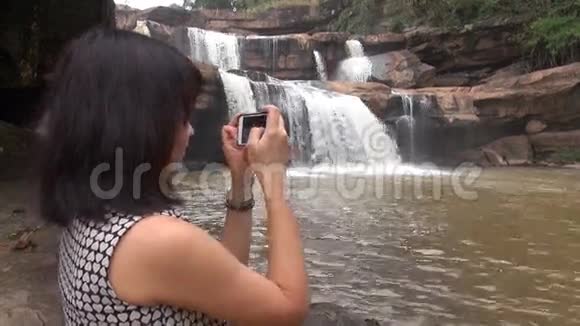 美丽的年轻女子用智能手机拍摄大自然视频的预览图