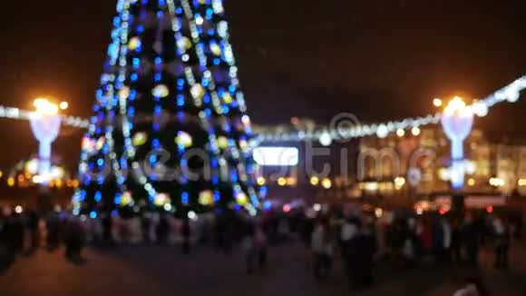 新年前背景镇广场模糊城市居民围绕圣诞树举行的晚间庆祝活动视频的预览图