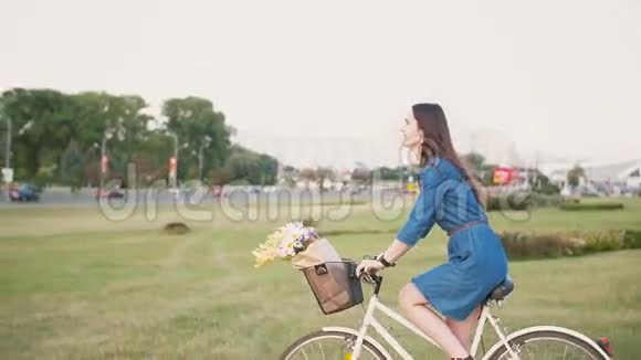 城市里一个头发长长的黑发女孩骑着一辆自行车花篮里放着鲜花慢悠悠地拍着的镜头视频的预览图