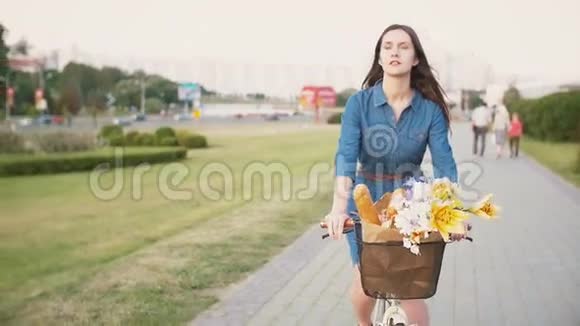 布鲁内特女孩骑着花篮骑着自行车在城市里探险慢的稳定的镜头视频的预览图