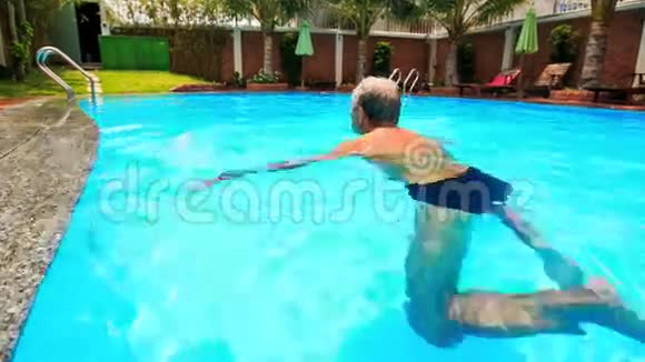 大胡子老人沿着椭圆形城市游泳池游泳视频的预览图