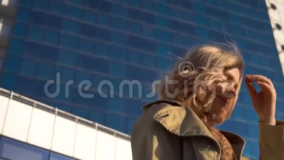 漂亮的年轻金发女郎穿着壕沟和高跟鞋带着老式手提箱在海军基地带着深蓝色视频的预览图