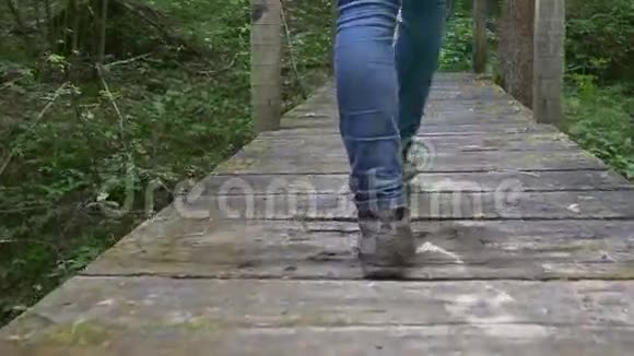 女徒步旅行者的腿穿过一座木桥视频的预览图