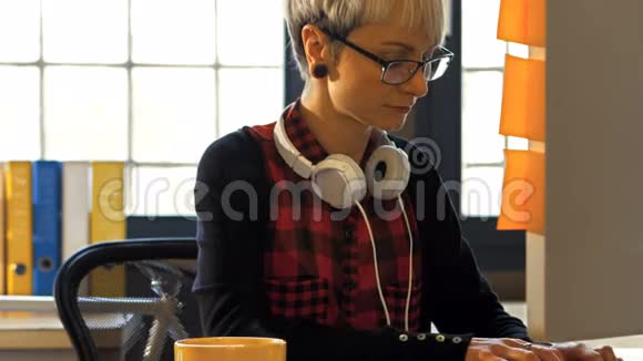 女平面设计师在喝黑咖啡的时候在电脑上工作视频的预览图