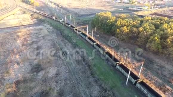 从空中俯瞰一列满载煤炭的货运列车无人驾驶的飞机越过横跨河流的货运列车视频的预览图