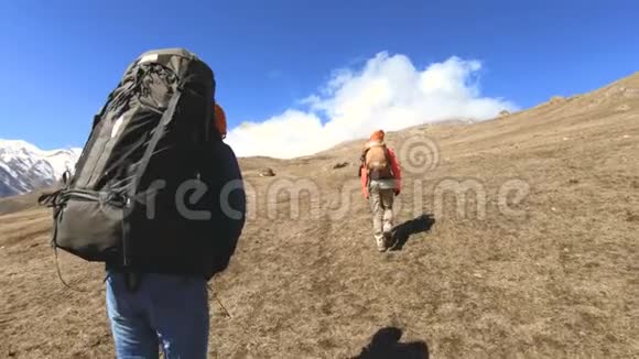 两个戴着帽子和太阳镜背包的游客摄影师带着相机在黄草上山视频的预览图