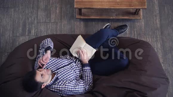 有魅力的男人躺在椅子上打电话视频的预览图