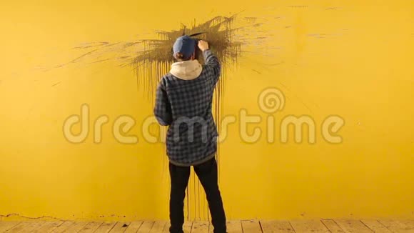 艺术家在黄墙上用黑色画笔描绘抽象的装饰视频的预览图