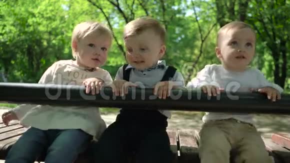 三个快乐的孩子坐在公园的长凳上视频的预览图