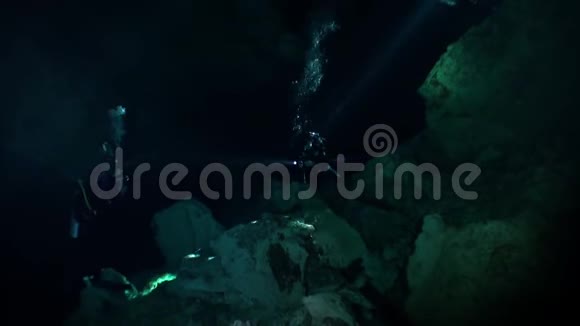 在墨西哥尤卡坦的黑暗洞穴里用手电筒游泳视频的预览图