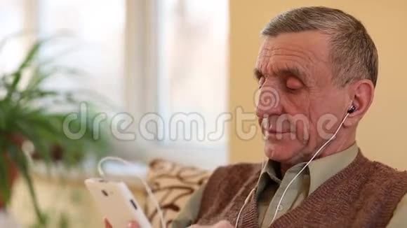 戴着白色智能手机的老人说话微笑和手势视频的预览图