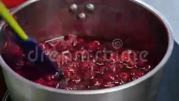用勺子在金属平底锅中特写搅拌樱桃果酱把自制的樱桃果酱烧好烹饪自制视频的预览图