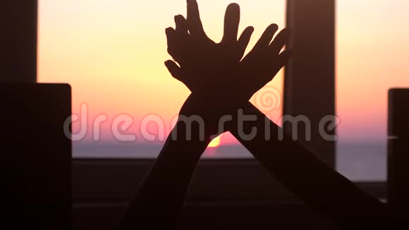 一个男人和一个女人互相牵着手在窗前的大海和美丽的日落的背景下慢慢慢慢视频的预览图