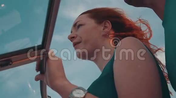 年轻漂亮的红发女孩坐在摩托艇上夏天有风的夜晚蓝天视频的预览图