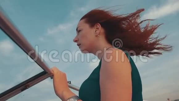 年轻的红发女孩在摩托艇上夏天有风的夜晚日落蓝天视频的预览图