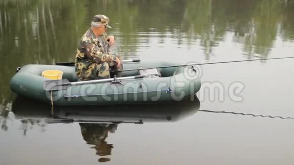 那个在湖边打电话的人在充气船上拿着鱼竿的渔夫视频的预览图