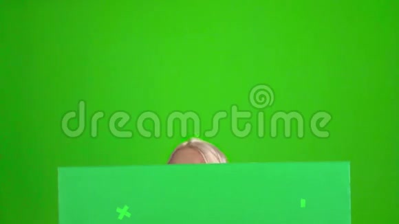 巴伐利亚女孩从绿色留言板后面往外看绿色屏幕慢动作视频的预览图