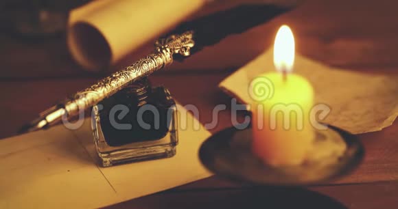 带有蜡烛的棕色木桌上的老式琴笔和墨水壶视频的预览图