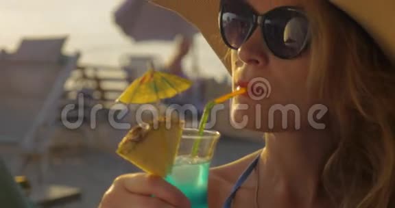 戴帽子和太阳镜的女人喝鸡尾酒视频的预览图