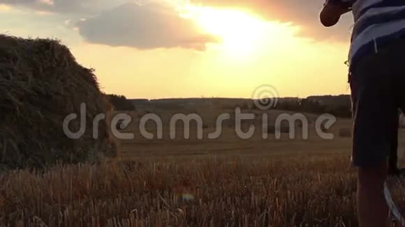 日落时分骑着自行车在田里的男孩在干草堆附近视频的预览图