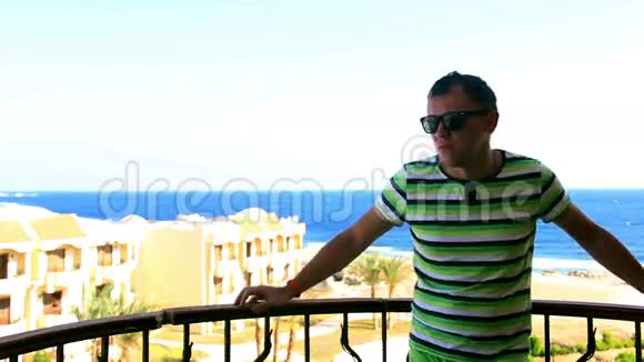 男人很紧张很生气在阳台上戴着太阳镜可以看到海景视频的预览图