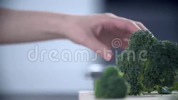 女人的手在木桌上把花椰菜切成小块视频的预览图