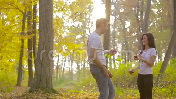 在秋天公园恋爱的年轻夫妇男人和女人玩苹果视频的预览图