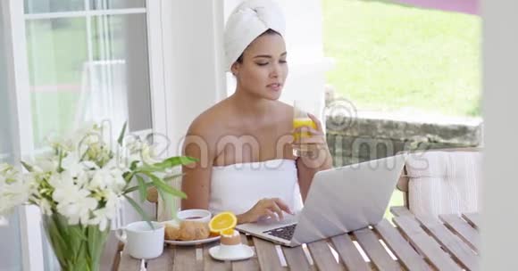 带手提电脑的女士正在吃早餐视频的预览图