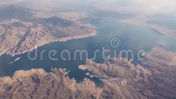 在飞往美国拉斯维加斯的商业航班上在白云上方飞行下面有山脉和湖泊米德视频的预览图