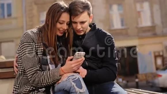 快乐夫妇在街上玩时髦的智能手机游戏视频的预览图