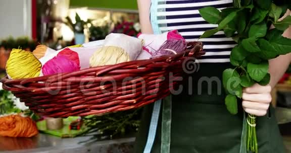 花店里的女花匠拿着一束粉红色的玫瑰和细绳视频的预览图