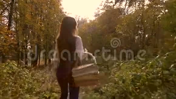 瘦削的黑发女孩走在秋天的森林里拿着一个野餐篮4Ksteatam视频视频的预览图