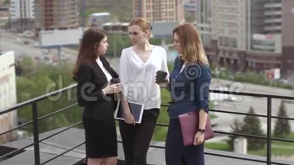 女孩们在屋顶上聊天三个有魅力的朋友在工作休息时闲聊慢动作视频的预览图