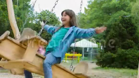微笑的女孩在操场上玩得很开心孩子们夏天在户外玩耍在外面骑着秋千的青少年视频的预览图