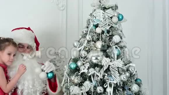 圣诞老人带着漂亮的小女孩装饰圣诞树视频的预览图