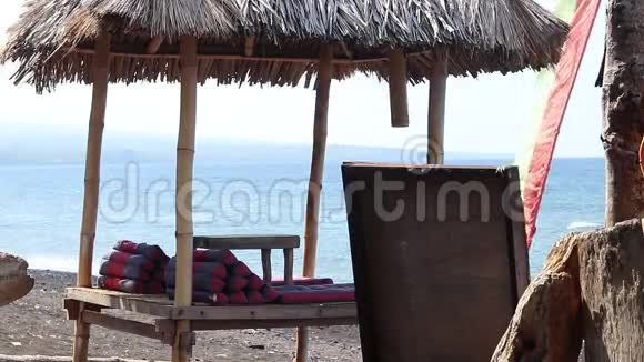 在巴厘岛浪漫的海滩上木制的遮风避雨的凉亭巴厘岛以东阿米德有黑色火山沙的海滩视频的预览图