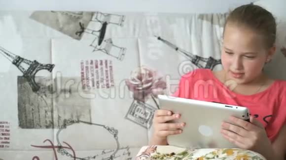 少女在床上使用数码平板电脑视频的预览图
