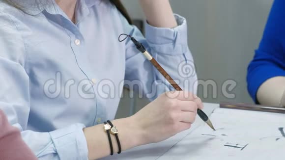 女子教青少年如何在书法课上写汉字学生用毛笔墨水和视频的预览图